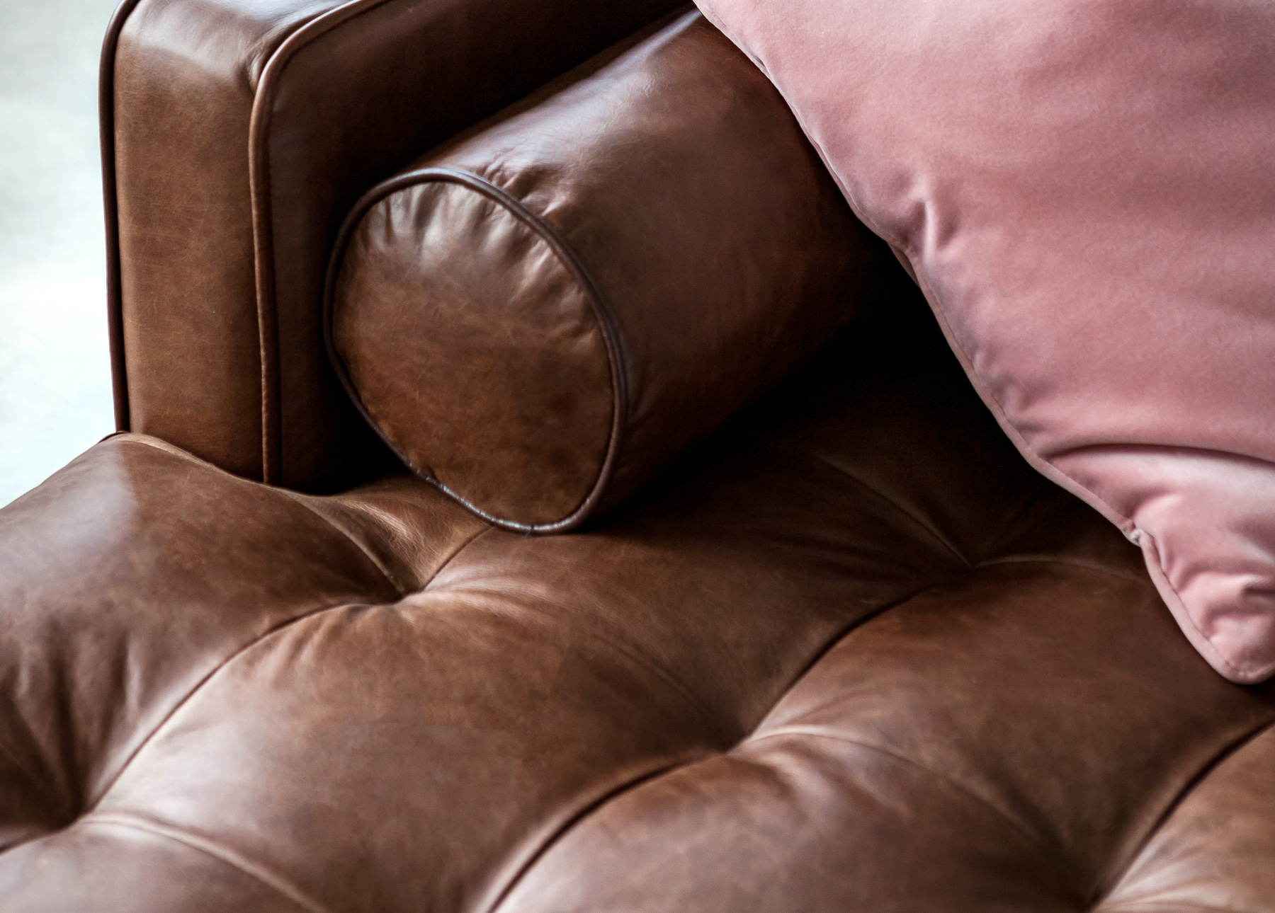 Chocolate Brown leather sectional sofa with pink velvet pillow