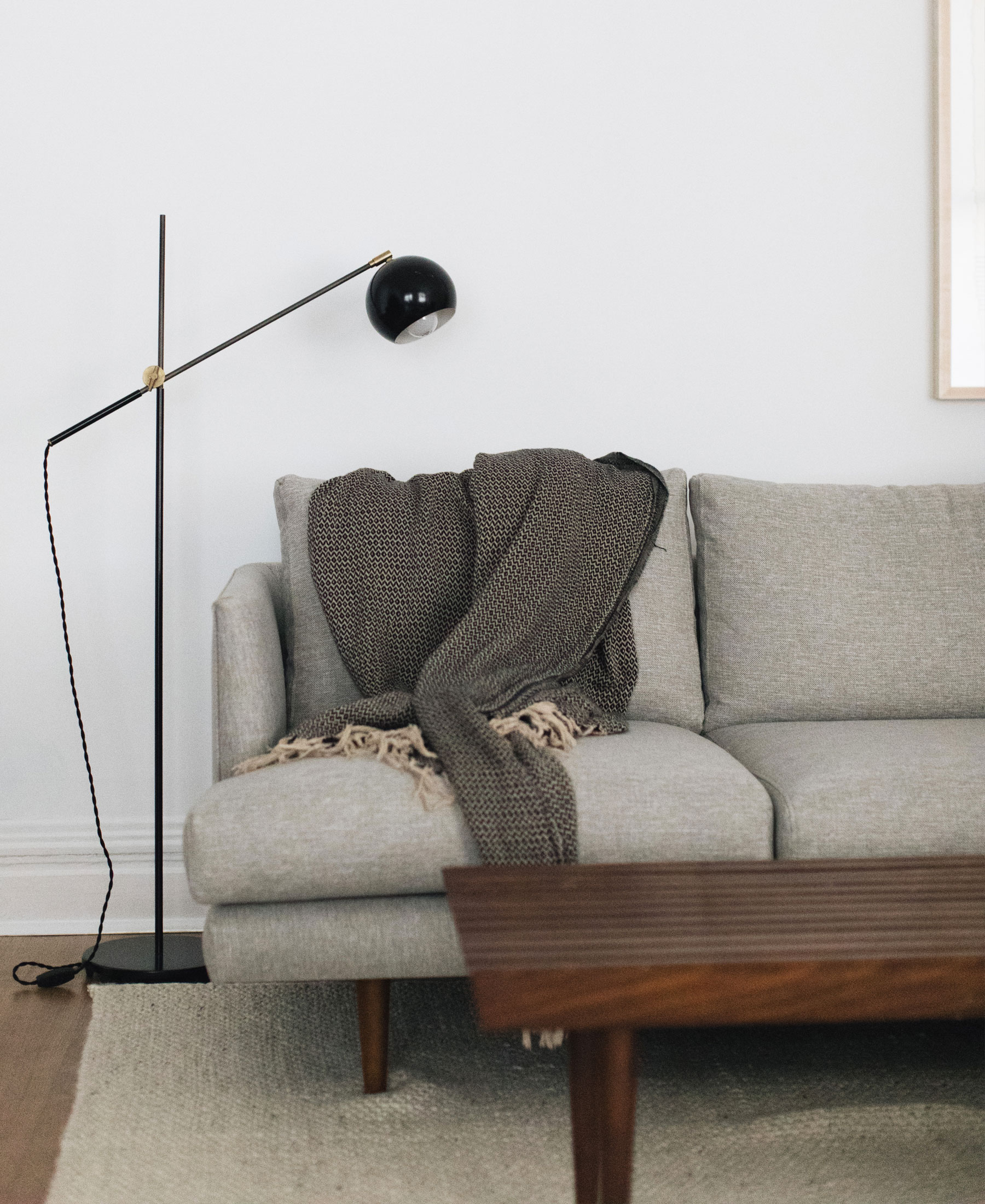 Angular mid-century modern lighting and a gray sofa.